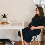 Sen o wężach w domu: granice, strach i transformacja energii rodzinnej Ciężarna kobieta w salonie siedzi przy stole z dwoma psami