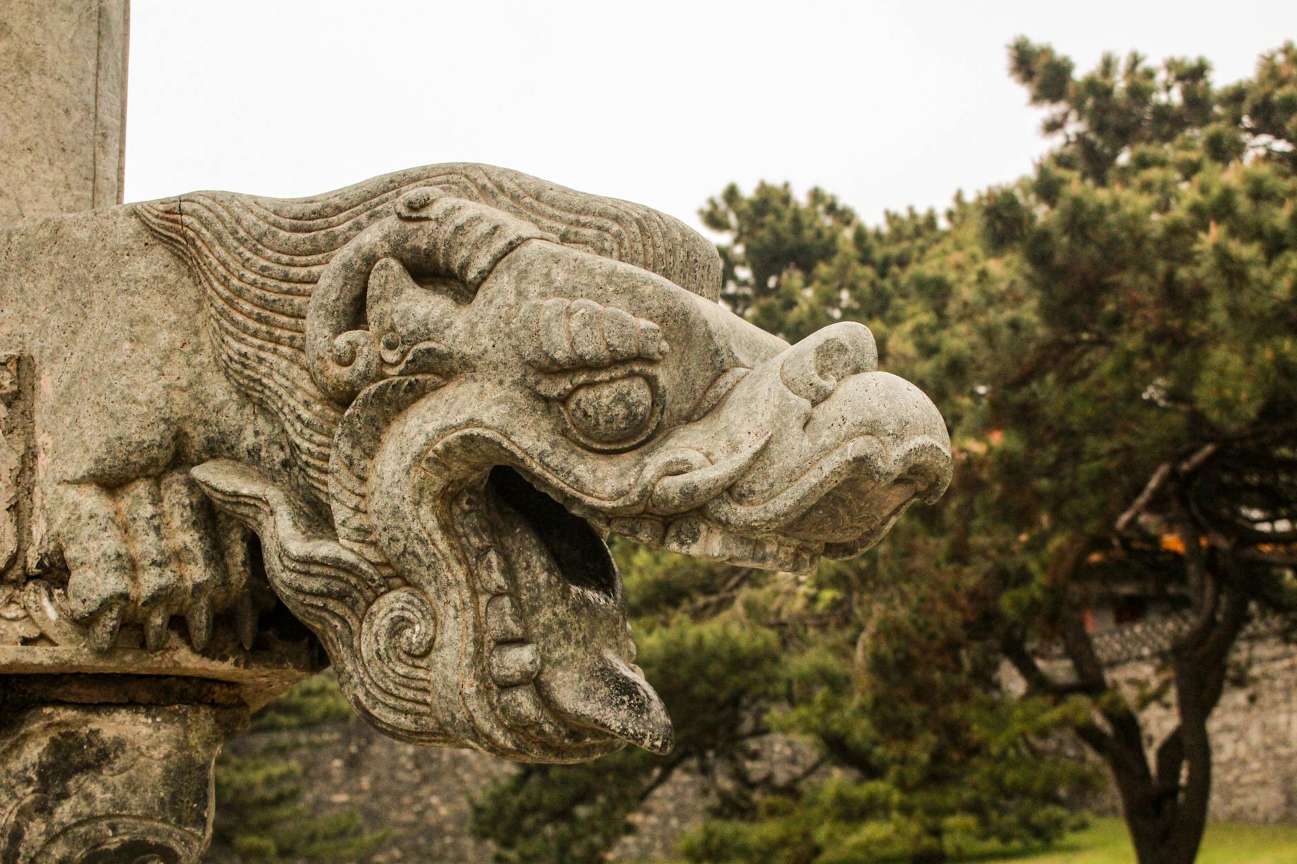 Kamienna rzeźba smoka na tle drzew