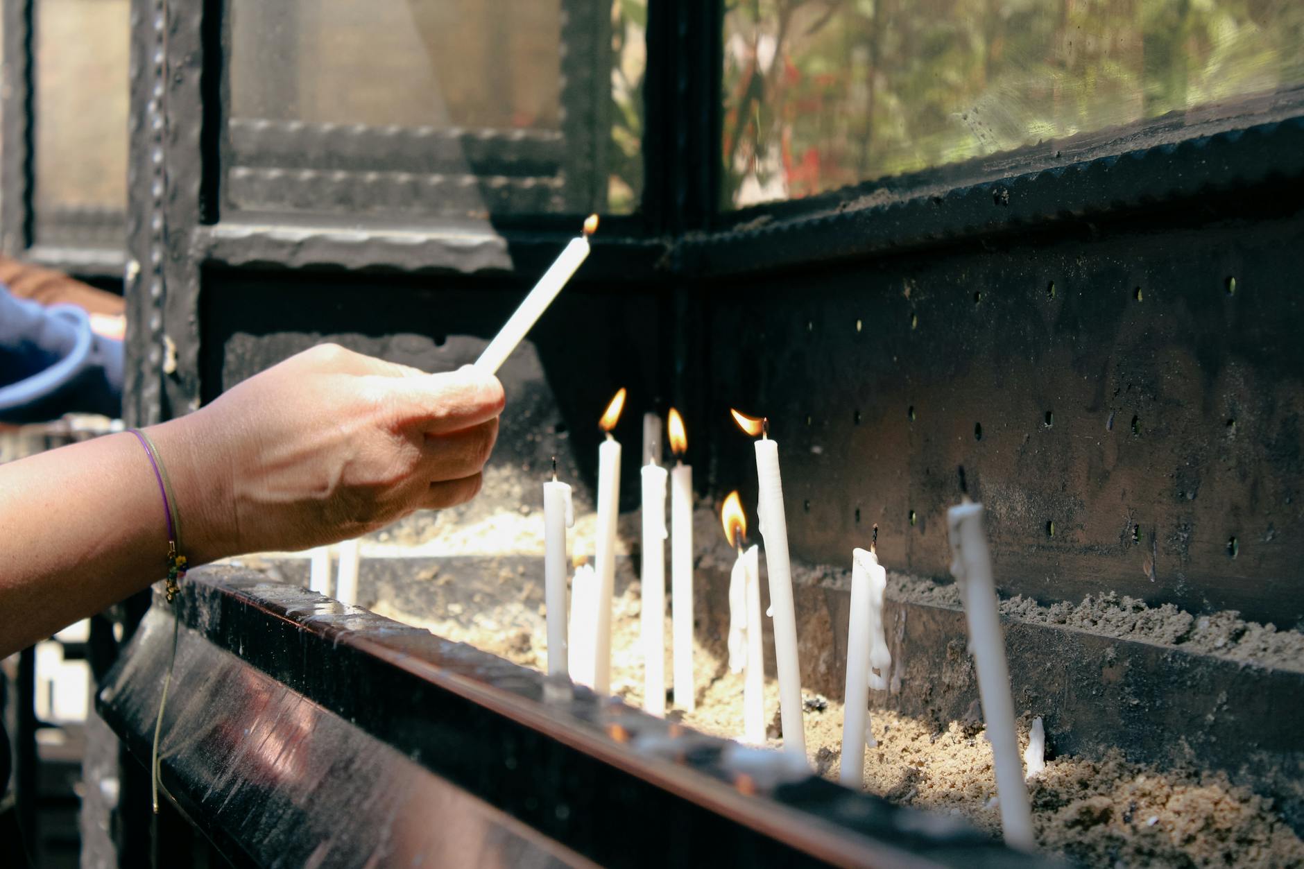 Dłoń zapalająca świece w rytualnym, pełnym skupienia otoczeniu