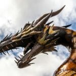 Monumentalny posąg smoka sfotografowany z dołu na tle pochmurnego nieba