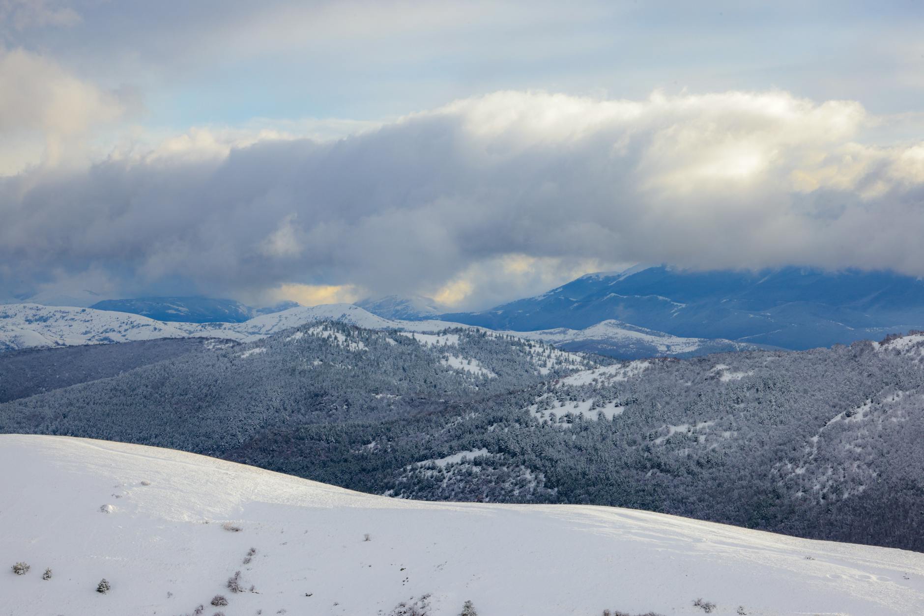 Zimowe górskie szczyty pokryte śniegiem pod dramatycznym niebem
