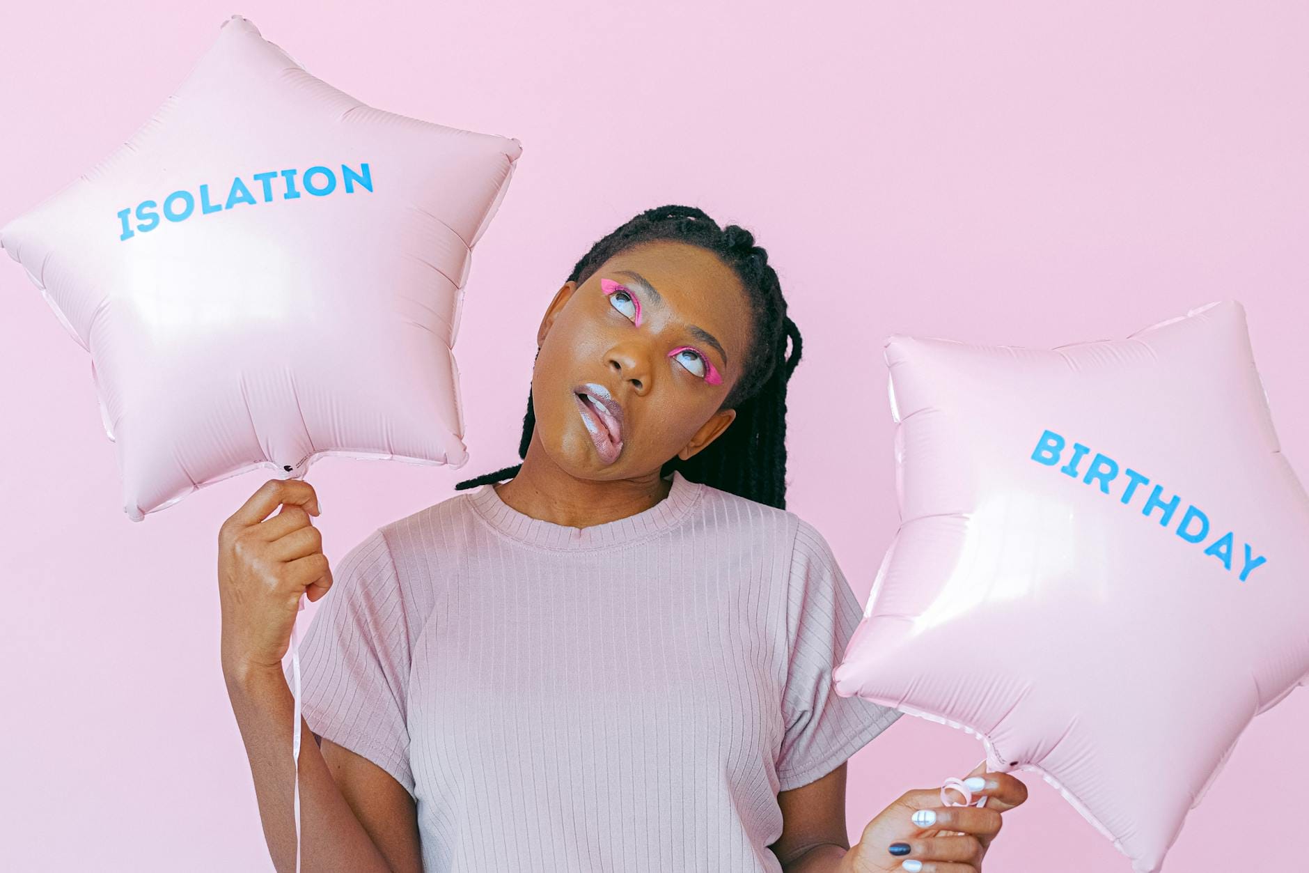 Kobieta z balonami w kształcie gwiazd na różowym tle