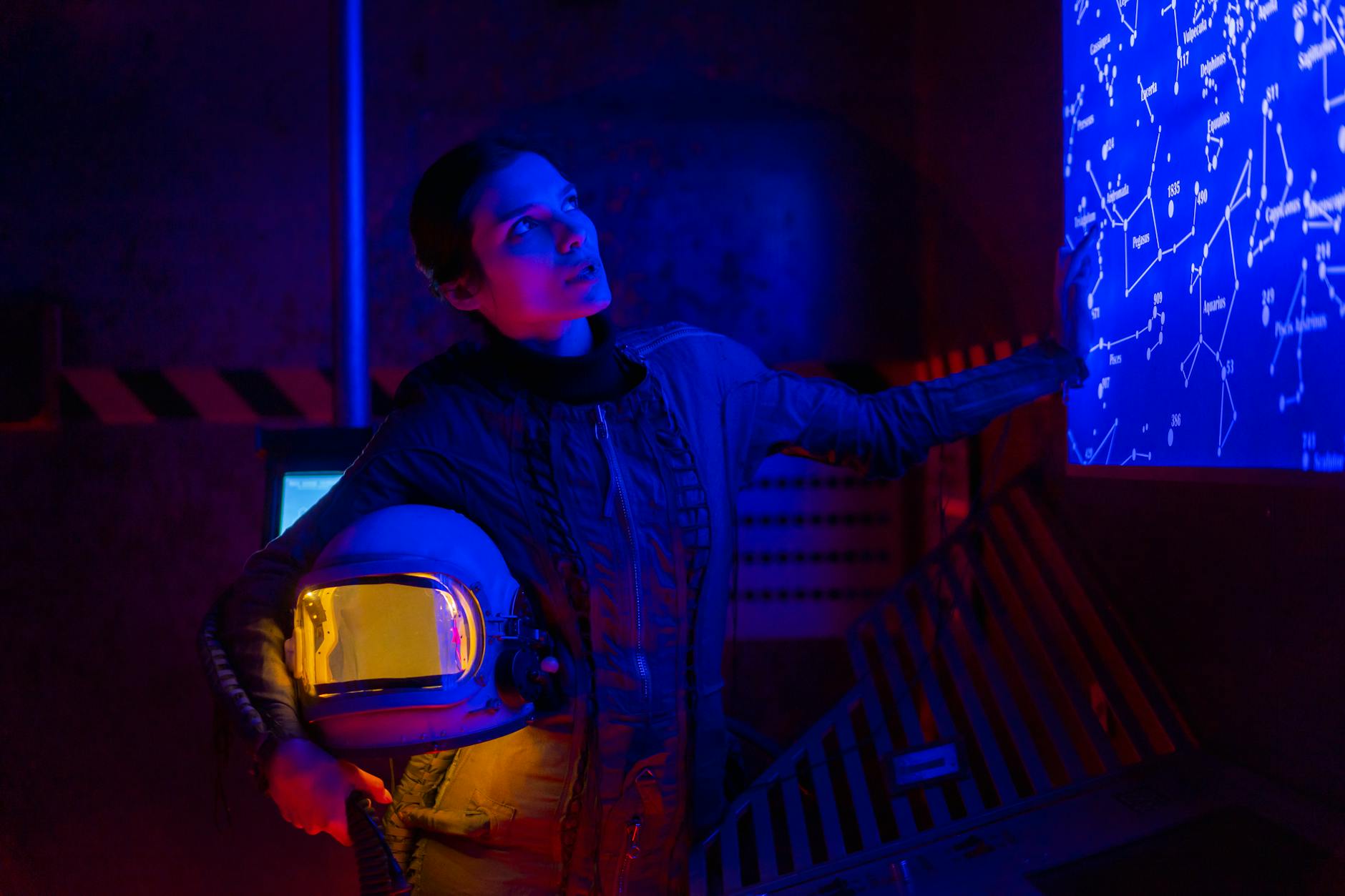 Kosmonautka przy neonowej mapie gwiazd trzyma hełm w futurystycznym wnętrzu