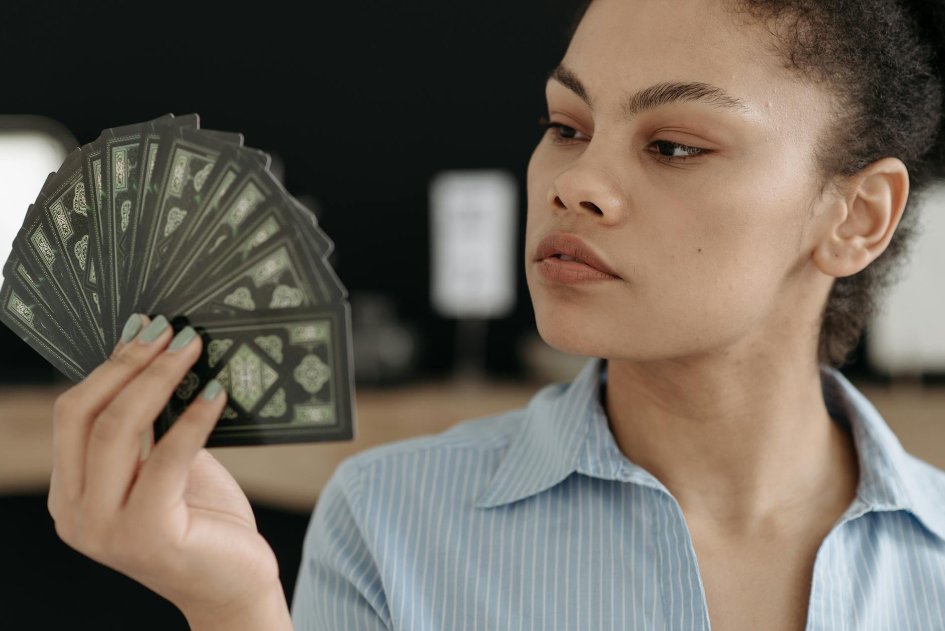 Skupiona młoda kobieta ogląda rozłożone karty tarota